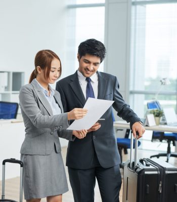 man-woman-business-suits-standing-office-with-suitcases-looking-together-document
